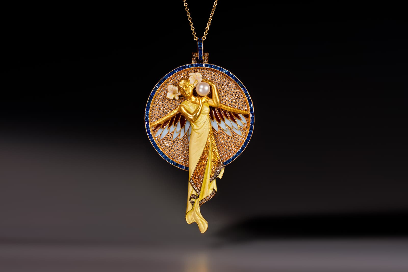 Epoque Fine jewels Art Nouveau pendant depicting a winged maiden in white enamel, pearls, rose cut diamonds and sapphires, by Masriera Hermanos, circa 1909
