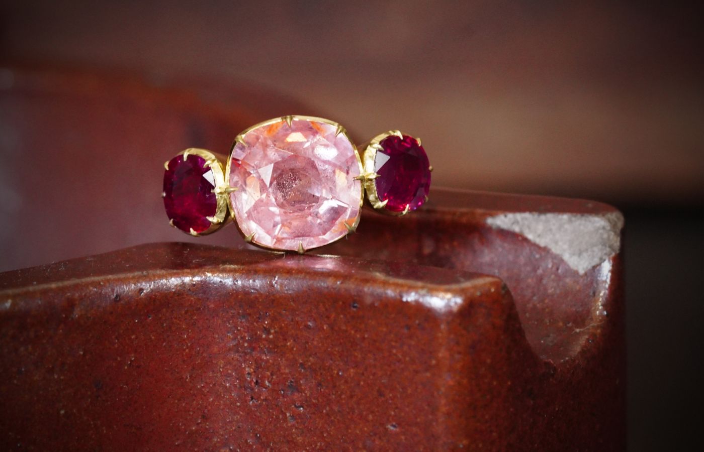  Jogani three-stone ring with a central Padparadscha sapphire of almost 7.38 carats, set with two rubies in yellow gold